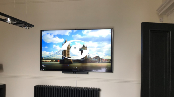 Customer's AV installation with System Video logo on screen imposed on a London Tower Bridge background picture. ClickShare and Bose VB1 videobar fitted underneath screen.